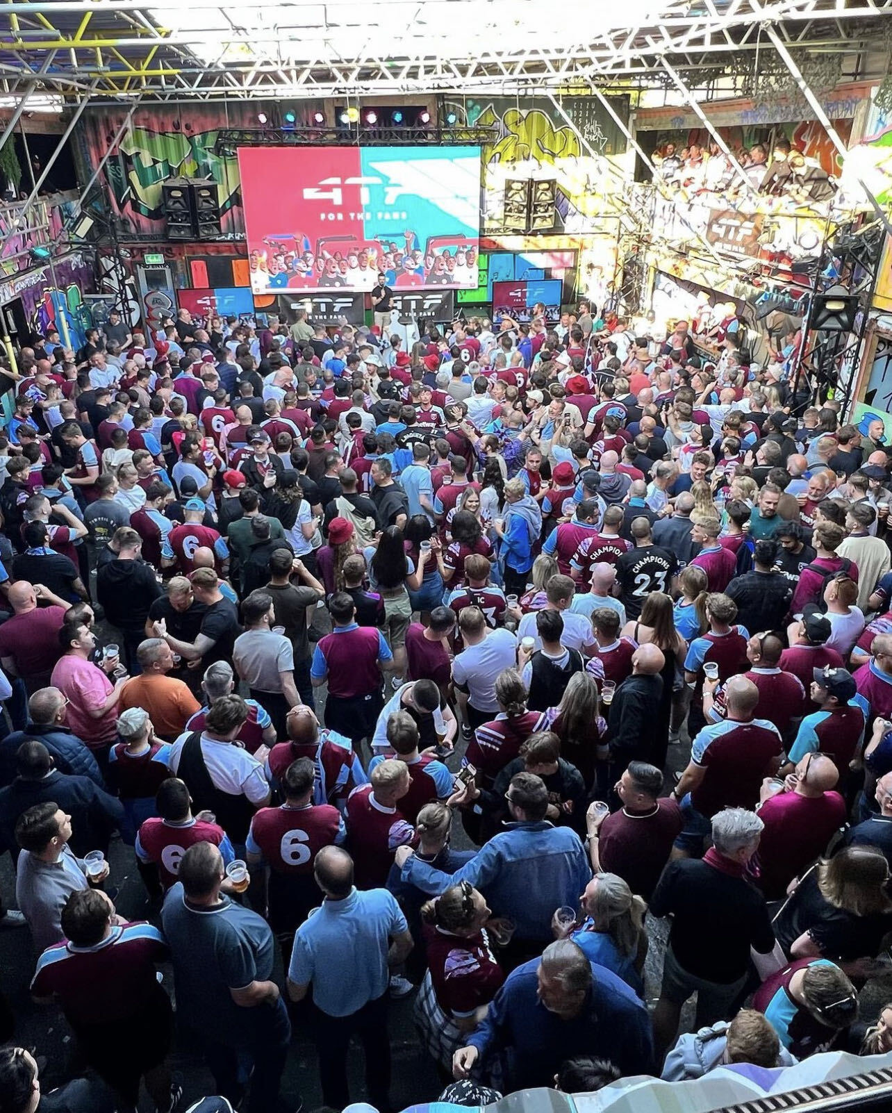 Packed crowd at a West Ham fanzone watching the big screen